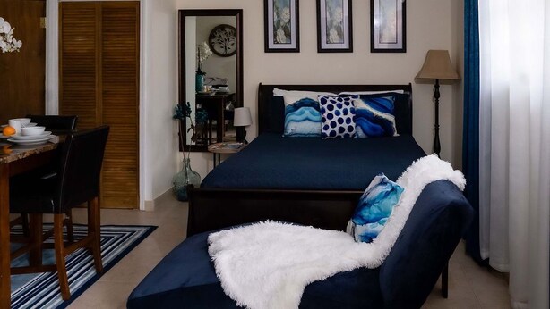 Un dormitorio con cama, una silla, un escritorio y un armario.