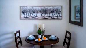 Una mesa de comedor con dos sillas, un cuadro en la pared y un florero con velas.