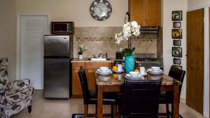 Una cocina compacta equipada con refrigerador, microondas, estufa y una mesa de comedor para cuatro.