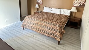 Een slaapkamer met een groot bed, twee nachtkastjes met lampen en bloemistisch kunstwerk aan de wanden.