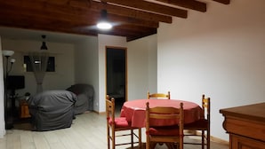 Un comedor con una mesa redonda y sillas, un ventilador de techo y una ventana con cortinas.