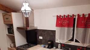 Cocina compacta con estufa, lavamanos y armarios de madera.