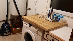Un espacio pequeño para la lavandería, con lavadora, aspiradora y un mostrador de madera.