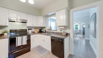 A modern kitchen with white cabinetry, a stainless steel stove, and a dishwasher.
