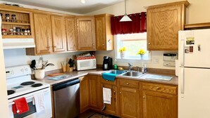 Una cocina con armarios de madera, estufa blanca, lavavajillas, microondas y refrigerador.