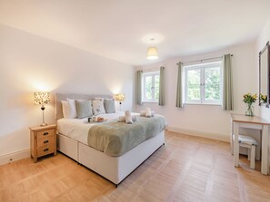 A bedroom with a bed, bedside tables, a desk, and a window.