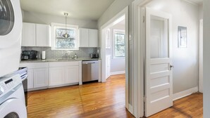 A modern kitchen with white cabinets, a dishwasher, and a built-in oven.