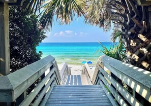 A wooden staircase leading to a beach with clear turquoise water.