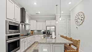 Una cocina moderna con armarios blancos, electrodomésticos de acero inoxidable y una isla central con asientos.