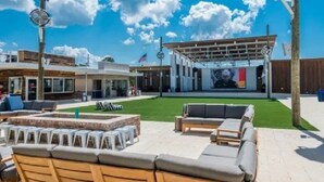 Un espacio exterior con sillas tipo lounge y una chimenea, un porche cubierto y un edificio de diseño moderno.