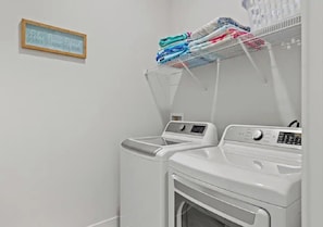 A laundry area with two washing machines and a drying rack.