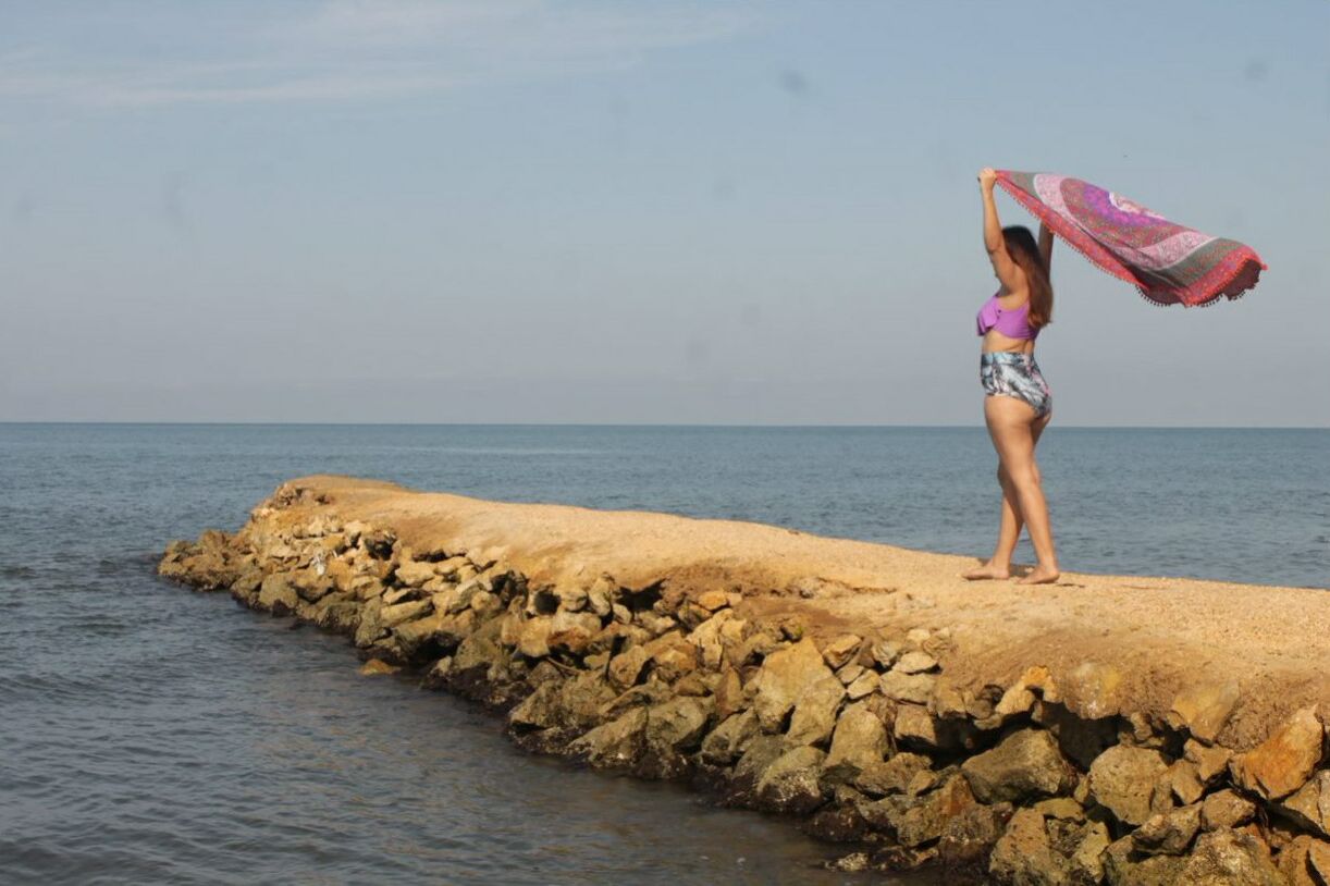 Una persona de pie en un muelle rocoso que se adentra en el agua.