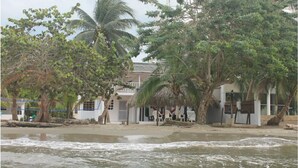 Una proprietà fronte spiaggia con struttura a tetto di paglia, palme e vista sull'oceano.