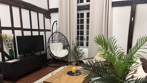Un salon avec un téléviseur, un fauteuil suspendu, une table basse et un canapé.