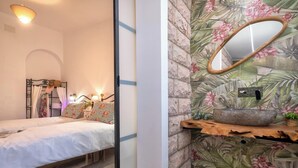 A bedroom with a bed, bedside table, and a nightstand with a lamp.