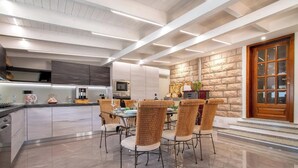 A modern kitchen with a central island, a dining area with wicker chairs, and a stone accent wall.