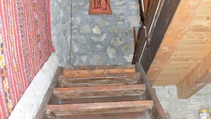 Un escalier en bois, avec des murs en pierre et un plafond en bois.