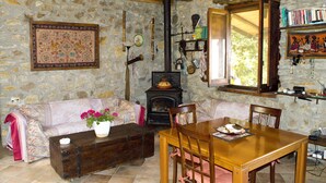 Une pièce rustique aux murs de pierre, avec une table en bois, des chaises, un canapé et une cheminée.