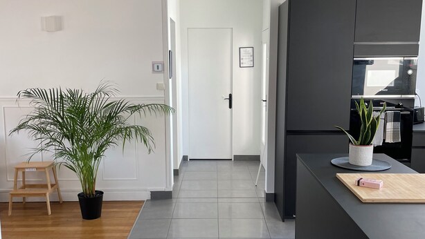 Eine moderne Küche mit eingebauter Mikrowelle, einer dunklen Arbeitsplatte und einem Blumentopf.