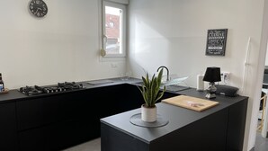 Eine moderne Küche mit schwarzem Arbeitsplatz, einem Gasherd, einer Topfpflanze und einer Kücheninsel.