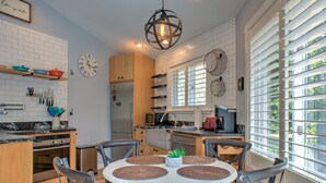 Une cuisine moderne avec des murs en briques blanches, des meubles en bois et une table de salle à manger ronde, accompagnée de quatre chaises.
