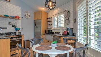 A modern kitchen with white brick walls, wooden cabinets, and a round dining table with four chairs.