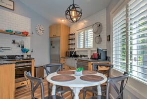 A modern kitchen with white brick walls, wooden cabinets, and a round dining table with four chairs.