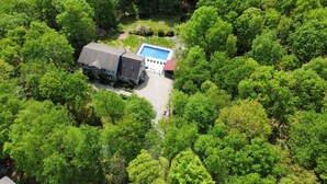 An aerial view of a property with a swimming pool, surrounded by dense greenery.