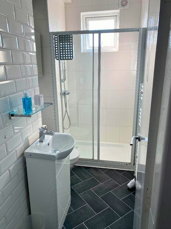 A bathroom with a glass-enclosed shower, a white sink, and a toilet.