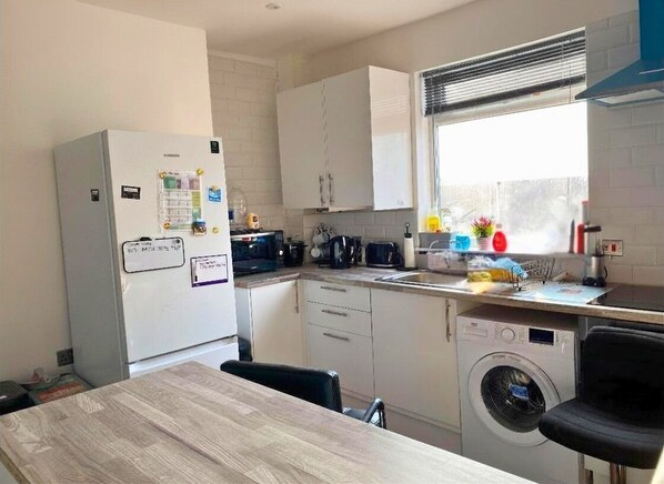 A compact kitchen with a refrigerator, microwave, sink, and washing machine.