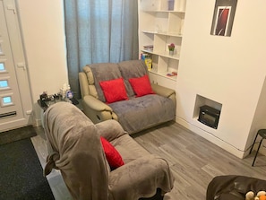 A living room with a sofa, a chair, a bookshelf, and a fireplace.