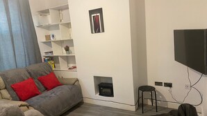 A living room with a sofa, a black bean bag chair, a television, and a fireplace.