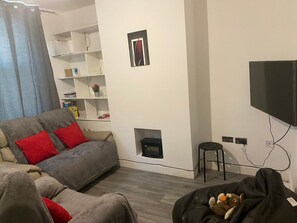 A living room with a sofa, a black bean bag chair, a television, and a fireplace. - Newly Refurbished 3-Bed House | 1 Tram Stop to NTU | Free Parking, Netflix (Nottingham)