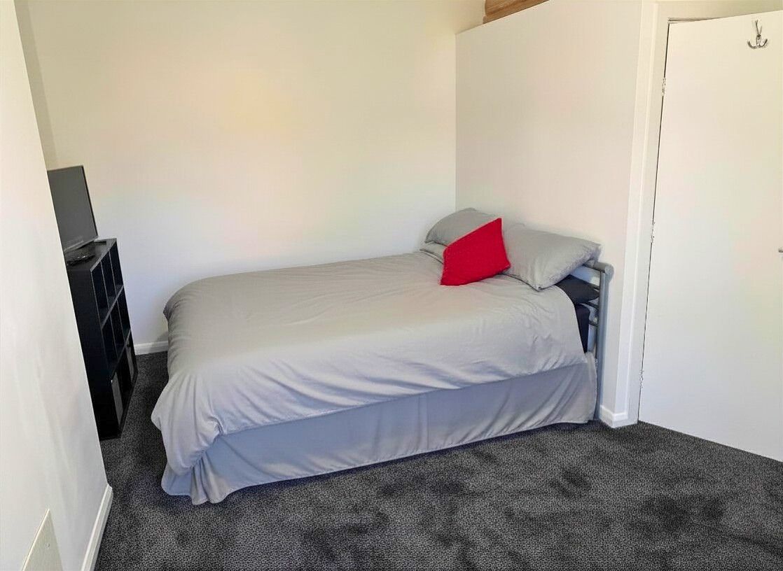 Une chambre à coucher avec un lit, une table de chevet et une porte.