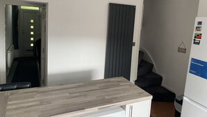 A compact kitchen with a wooden countertop, a white refrigerator, and a door leading to a hallway.