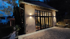 Una casa con un'ampia porta vetrata, un tetto in tegole e un vialetto in mattoni che conduce all'ingresso.