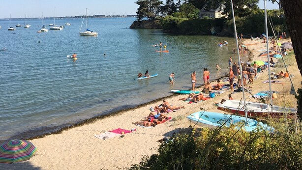 Ein Strand mit Booten, Menschen und Sonnenschirmen.