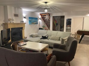 A living room with a fireplace, sofa, coffee table, TV, and a star-shaped ceiling light.