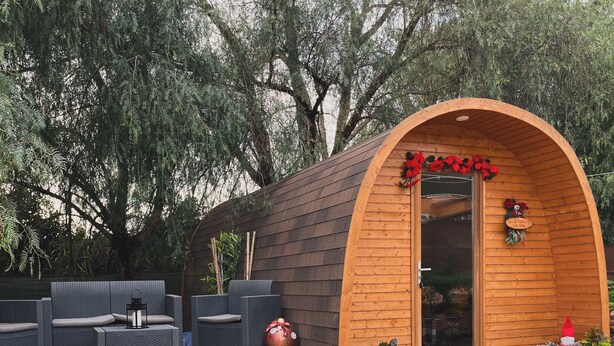 Uma cabana de madeira com entrada arqueada, área de estar externa e um deck.
