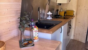Cozinha compacta com bancada de madeira, pia, fogão pequeno e geladeira compacta.