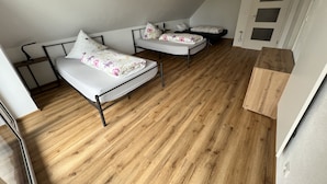 A small, compact room with two single beds, a wooden floor, and a white door with a window. - Vacation apartment "Saumpfad" 25 minutes to Legoland (Horgau)