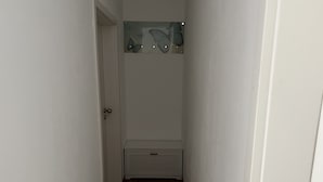 A narrow hallway with a wooden floor, a white door, and a small white cabinet. - Vacation apartment "Saumpfad" 25 minutes to Legoland (Horgau)