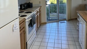 A kitchen with a refrigerator, microwave, stove, and wooden cabinets. - Condo in world class Leelanau Peninsula, Suttons Bay Beach Condo (Suttons Bay)