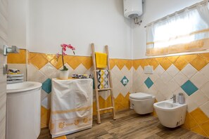 Une salle de bain équipée d’un lavabo, de toilettes, d’un bidet et d’un porte-serviettes.