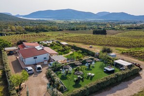 Un domaine viticole comprenant un bâtiment blanc, un espace extérieur aménagé avec des sièges et une piscine.