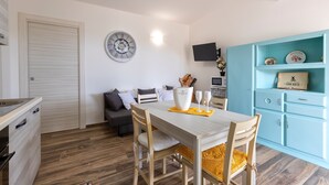 Un espace de vie compact comprenant un coin repas, une kitchenette et un meuble bleu agrémenté d’objets décoratifs.