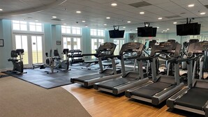 Un gimnàs amb cintes de córrer, aparells de musculació i un gran finestral.