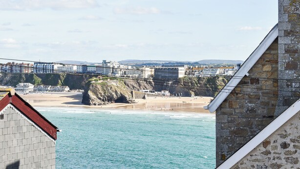 A coastal view with a beach, cliffs, and buildings in the background. - Apartment 15 Harvest Moon (Newquay)