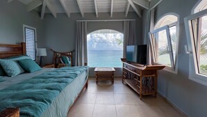 Ein Schlafzimmer mit Bett, Fernseher, Schreibtisch und Meerblick.