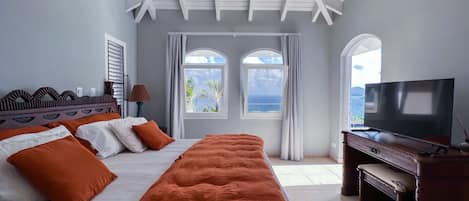 Un dormitorio con cama, televisor y vista al océano.